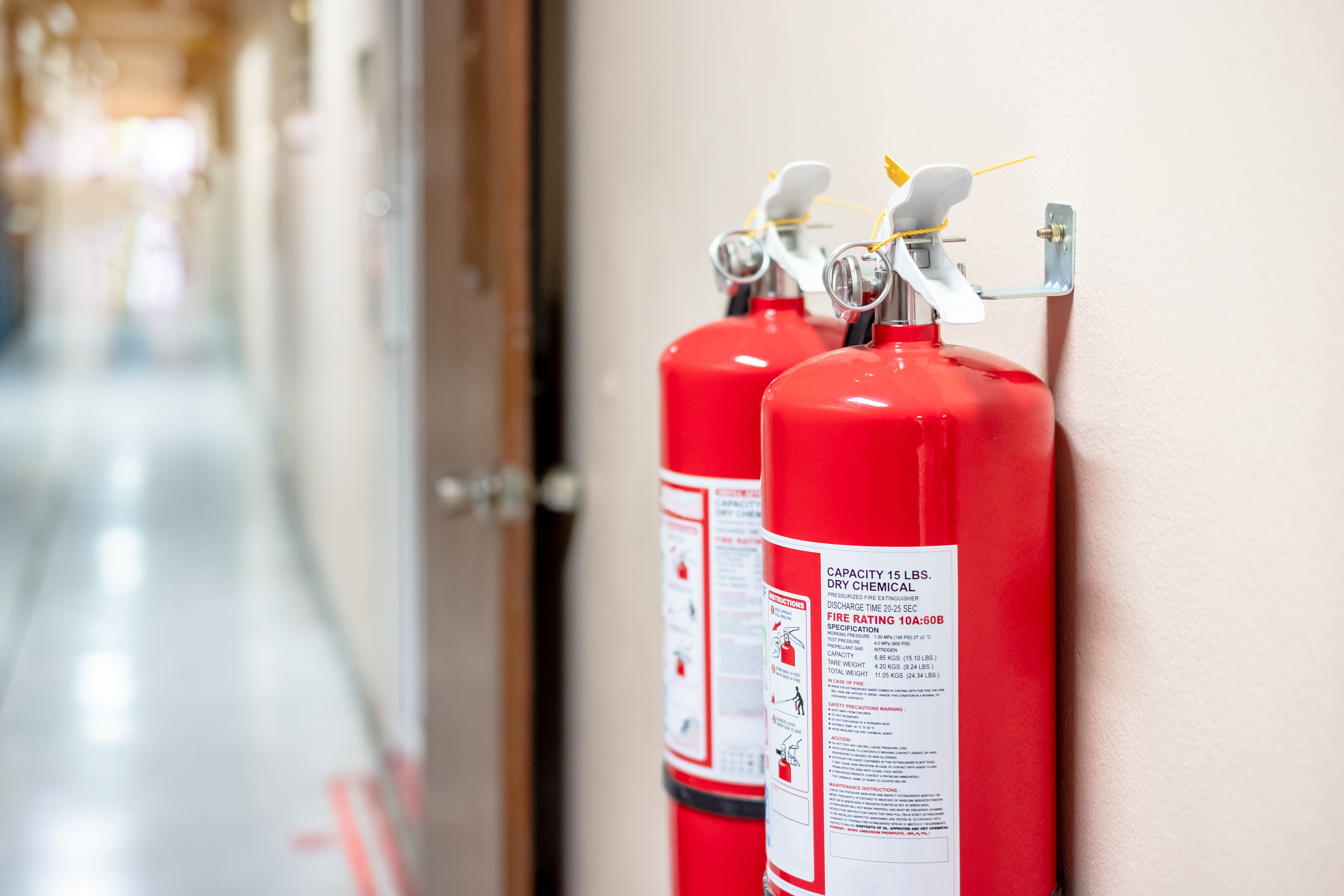 Wall-mounted fire extinguishers serviced in a Cornish commercial corridor