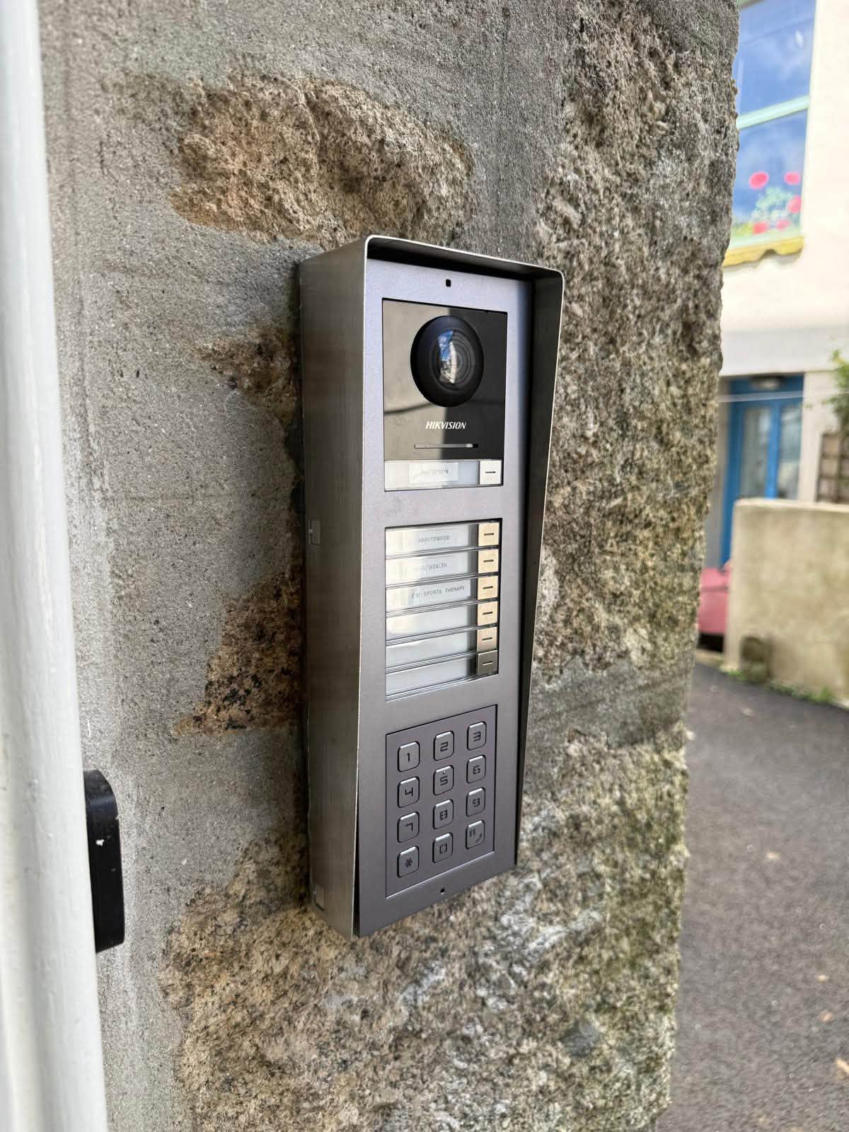 Hero shot: a door entry intercom panel mounted beside a building entrance